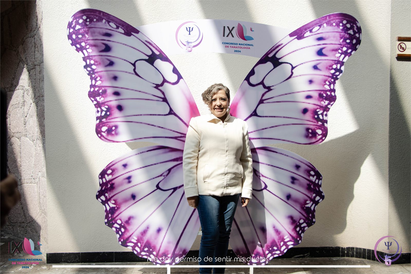 Asistente posando frente a unas alas de mariposa del IX congreso «Me doy permiso de sentir mis duelos»