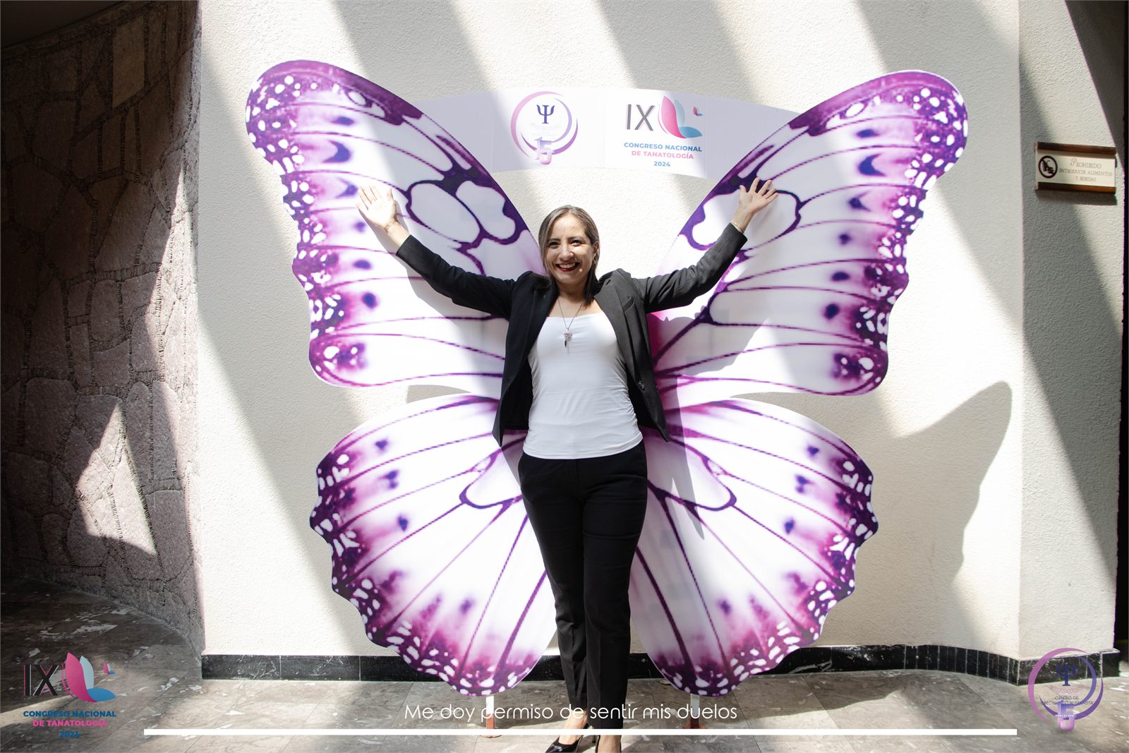 Foto con los brazos abiertos frente a las alas de mariposa del IX congreso