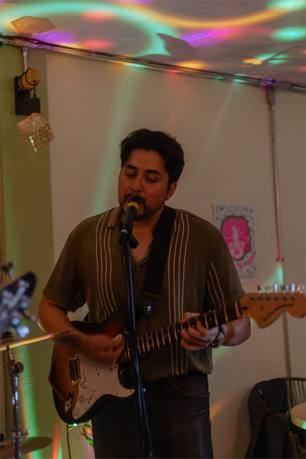 Guitarrista cantando bajo luces de colores en Zurda Foro Popular